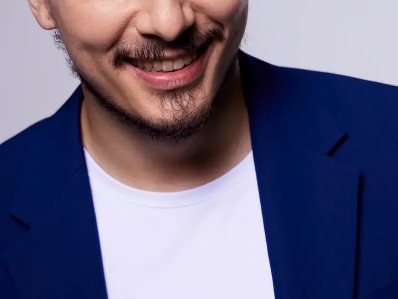 A cropped photo of an Asian man smiling and wearing a blue sport coat